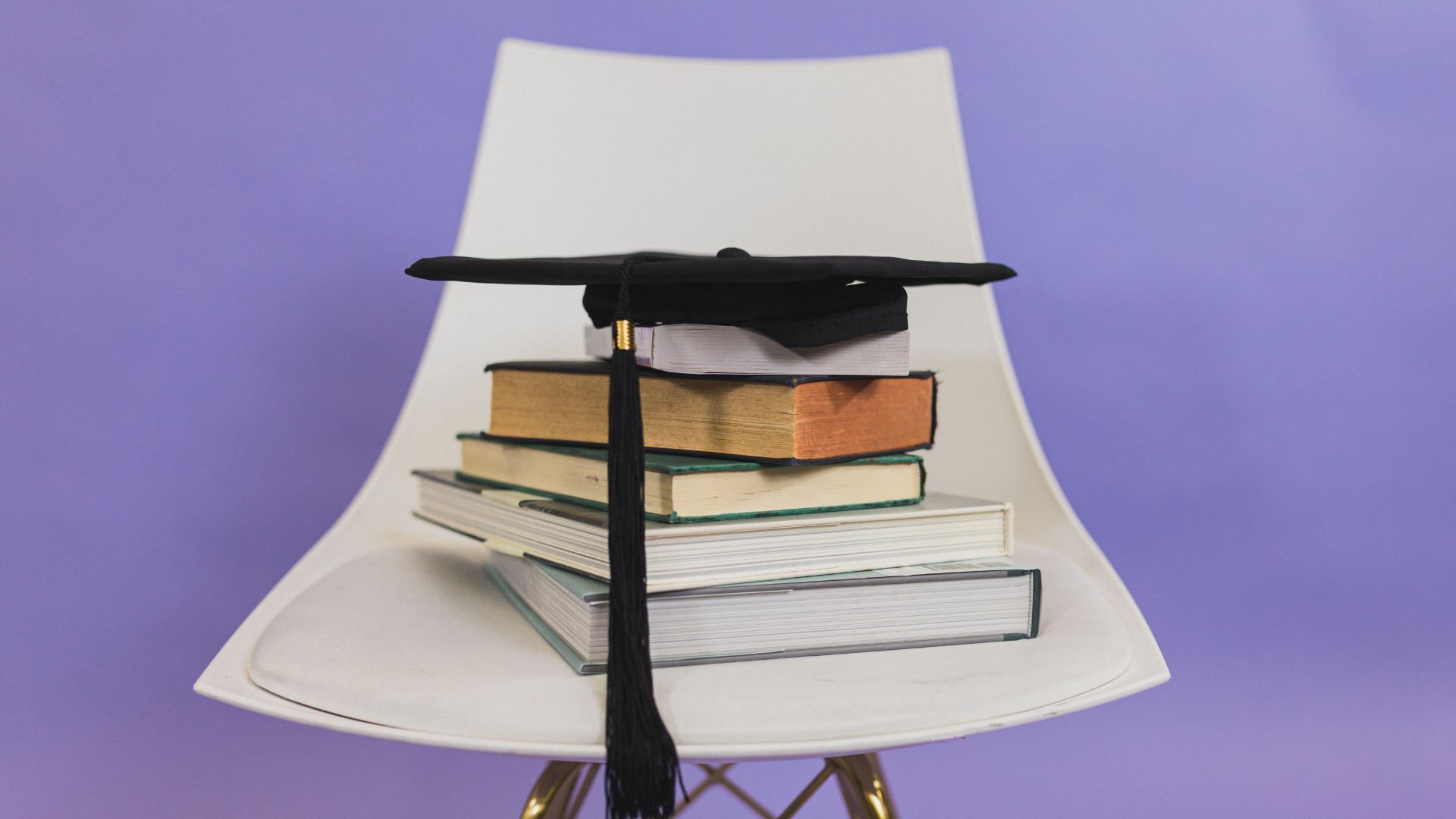 graduate cap on top of a stack of school books for college