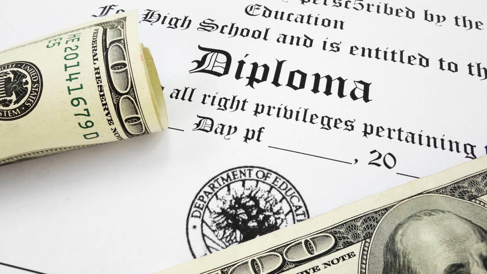 college diploma next to stacks of money bills currency