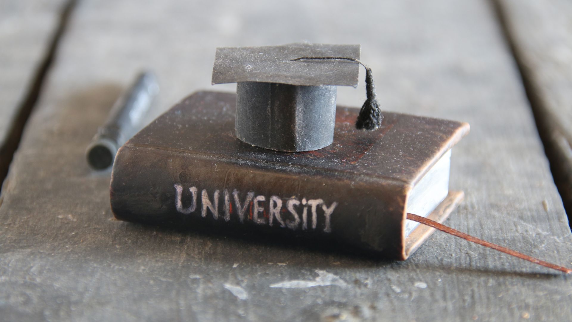 really cool miniature version of a university school book and graduation cap on a table